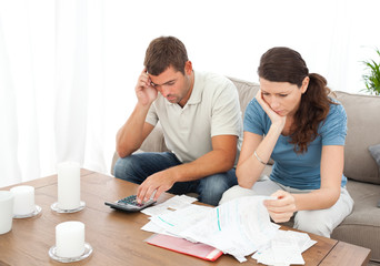 Desperate couple doing their accounts sitting on the sofa