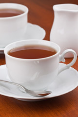 Black tea in mugs with saucers