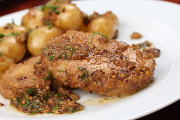 Roast pork on onion and mustard with baby potatoes