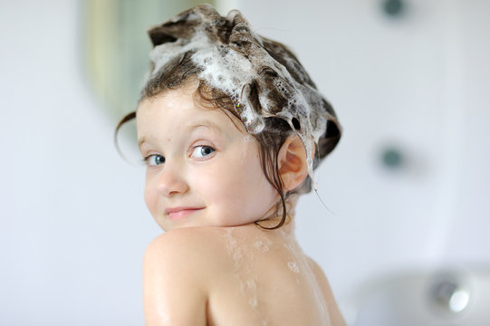 Small girl in bath with shampoo on her hair