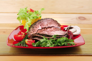 beef on red plate over wood