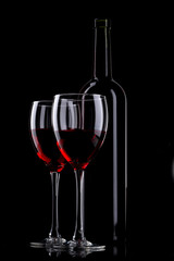 Bottle and glass of red wine on black background