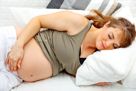 Beautiful pregnant woman sleeping  on sofa at home .