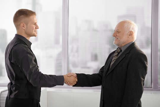 Senior and mid-adult businessman shaking hands