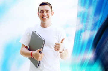 Young happy man or student with laptop and phone on the business