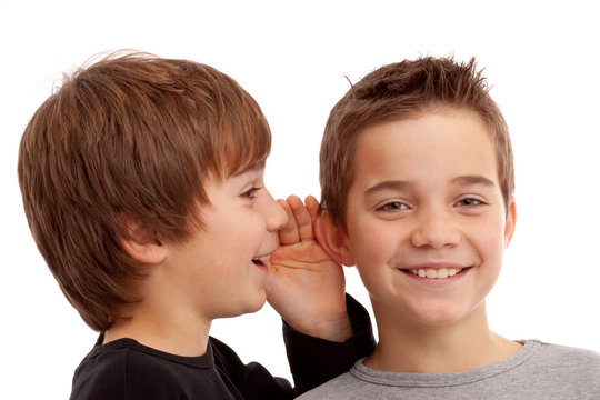 Zwei Jungen flüstern sich News und Geheimnisse ins Ohr