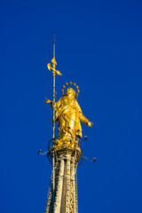 Holy Mary statue on top of Milan Dome in the blue sky