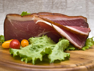 Breakfast close-up. Slices of bacon on the wooden plate with kni