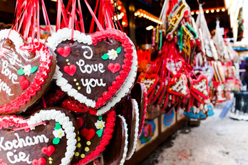 Baked gingerbread hearts hanging on red ribbon outdoors