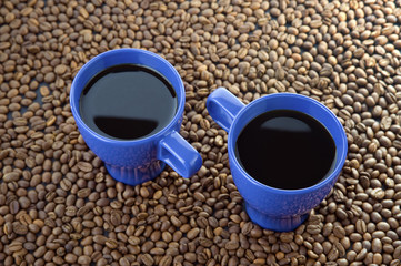 Two mugs filled with hot coffe with coffee beans background