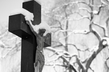Kreuz im Winter auf einem Friedhof s/w