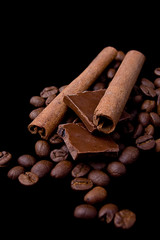 Cinnamon sticks over coffee beans and chocolate