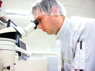 The men looks in stereomicroscope eyepieces