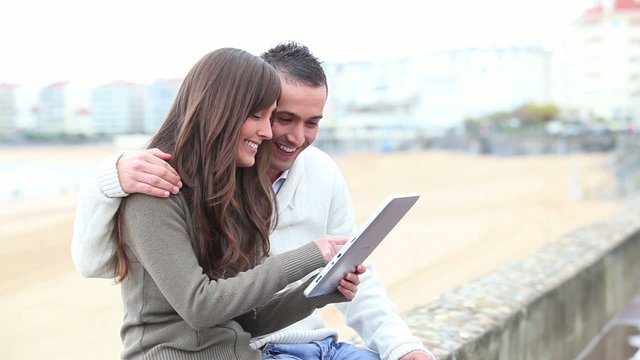 Young couple sitting outside with electronic pad