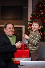 Boy giving christmas present to grandfather