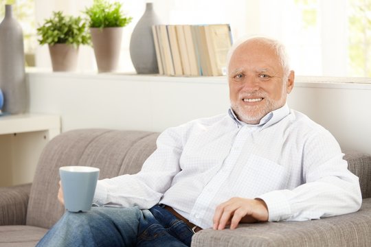 Smiling elderly man having coffee on sofa