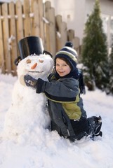 Kind umarmt lächelnd einen Schneemann