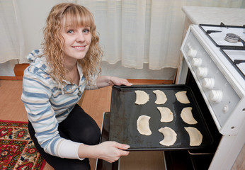 The girl puts pies in an oven for cooking