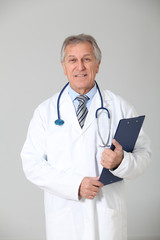 Senior doctor standing on white background