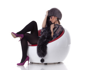 Young woman in fur  sit on armchair.