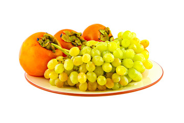 Grapes and persimmons on plate. Isolated on white