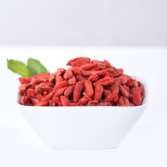 red dried goji berries on a bowl, on white background