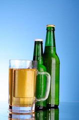 Bottles with beer and cup on blue background