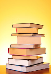 Books pile on the table and yellow background