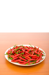 Hot peppers in the plate on wooden table