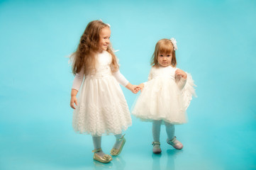 Fototapeta na wymiar Two little sisters in a fine white dresses