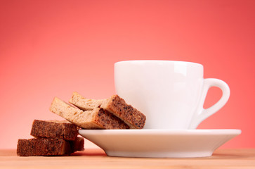 Cup of coffee and rusk on red background