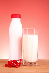 glass of milk and bottle on red background