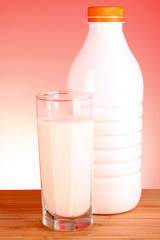 glass of milk and bottle on red background