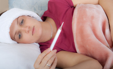 Obraz na płótnie Canvas Closeup portrait of young woman checking her body temperature
