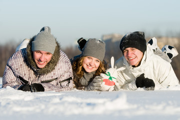 smiling young people lying in snowdrift