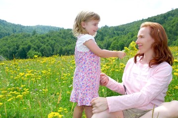 Daughter and mother playing in flowers meadow