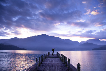 Man stand on a pier and watching the mountains and lake