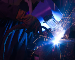 Dramatic blue-lit MIG welding close - obrazy, fototapety, plakaty