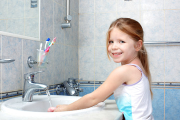 Little girl washing with soap in bathroom