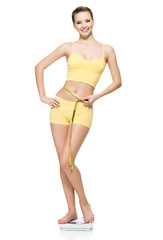 Fototapeta premium Woman standing on scales and measuring her slim waist