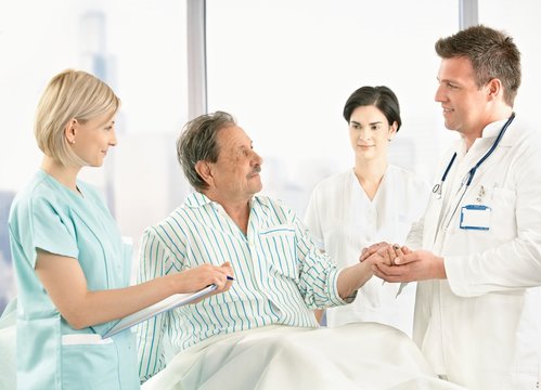 Doctors talking to old patient in hospital