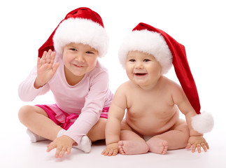 Two children wearing red Christmas caps and smile