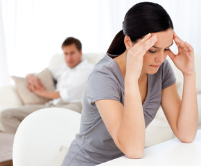 Man looking at his girlfriend having a headache sitting at a tab
