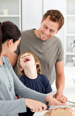 Fototapeta premium Little boy laughing while his mother cutting bread