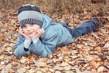 Ребенок мечтает, лежа на опавшей листве