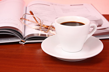 Cup of coffee, book, clock and calculator on wooden table