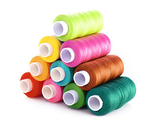 Pyramid of many-coloured bobbins of thread isolated on white