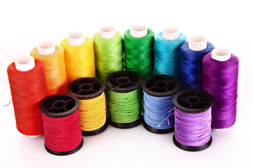 Semicircle of many-coloured bobbins of thread isolated on white