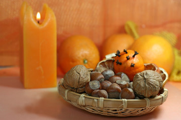 Oranges, Christmas nuts and candles in warm light.