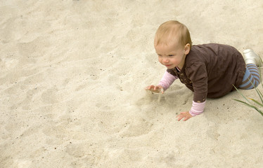 Sweet little toddler girl crawling on a sandy beach